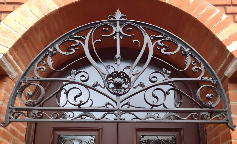 marquise de porte en fer forgé sur un mur en brique rouge